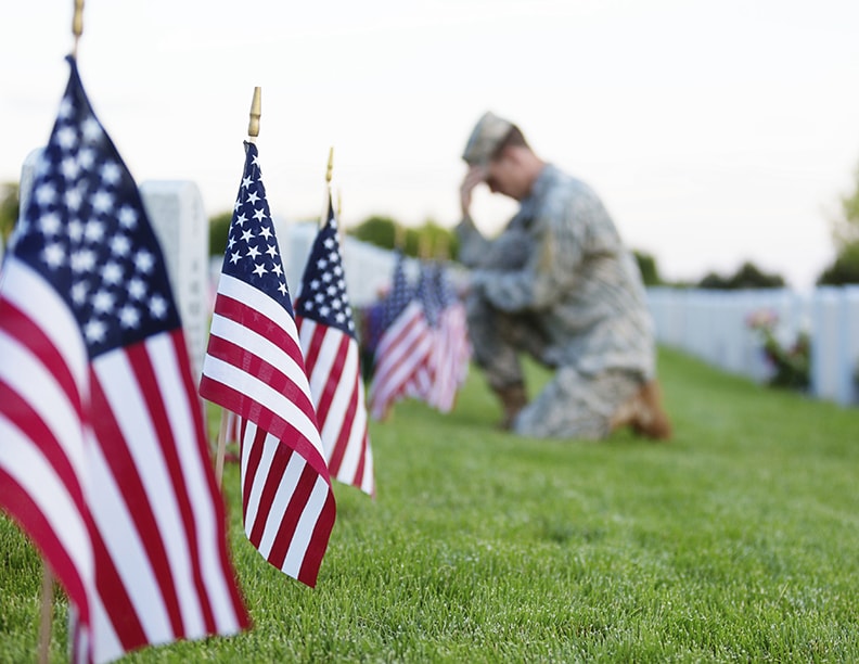 Soldier kneeing at a grave on flag day